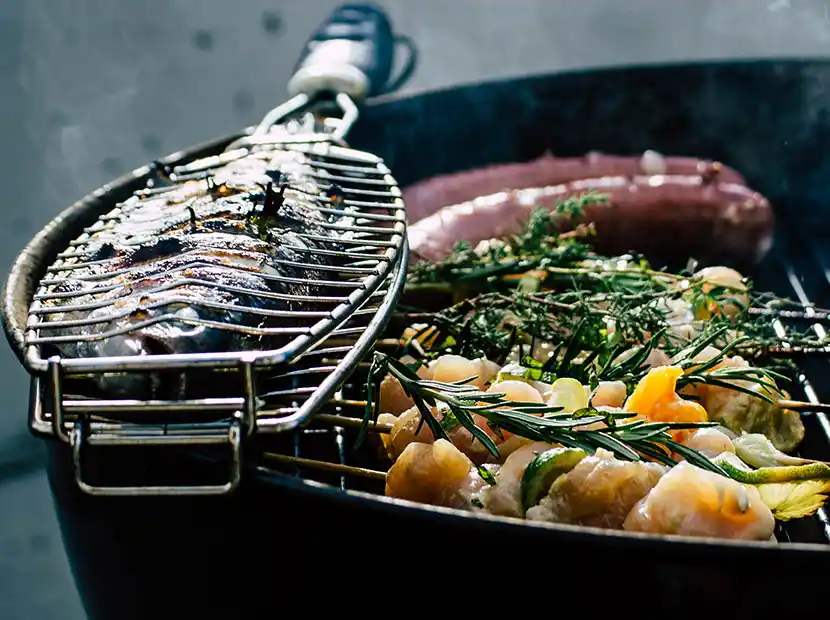 Grill mit Fisch, Würstchen, Garnelenpießen und Rosmarin.