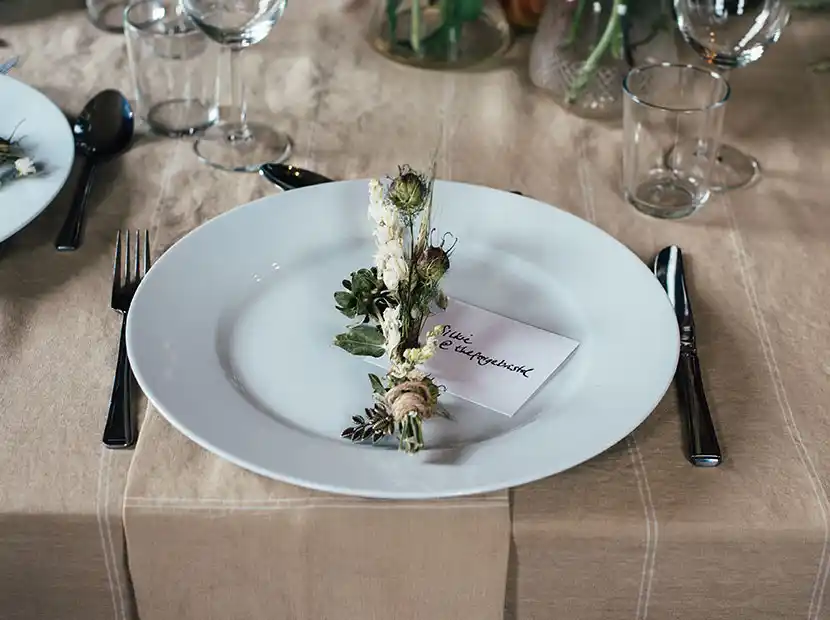 Catering für Hochzeit mit Tischgedeck mit Blumengesteck und Platzkarte.