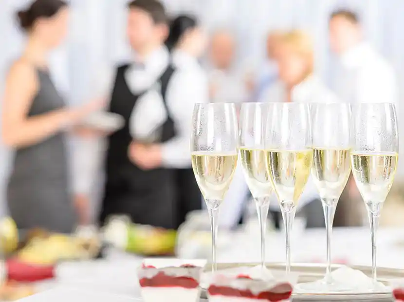 Gläser mit Sekt und Leute im Hintergrund.