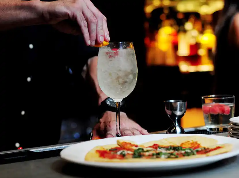Barkeeper mit Hugo und einer Pizza.