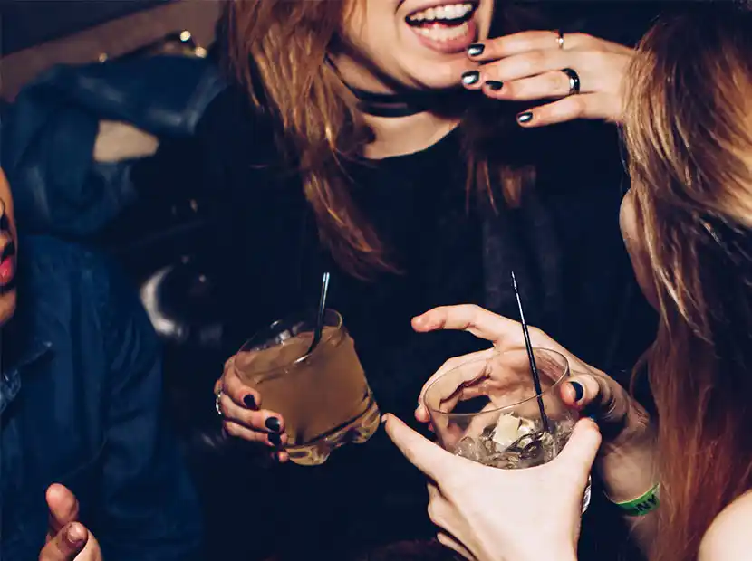 Party - zwei Frauen unterhalten sich mit Cocktails in der Hand.