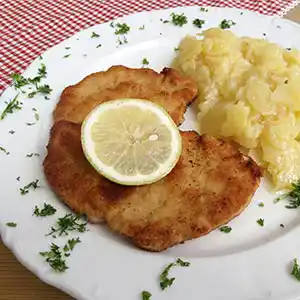 Teller mit paniertem Kalbfleisch und Kartoffelsalat.