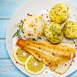 Teller mit Kabeljau, Zitronen-Kartoffel und Gemüsereis.