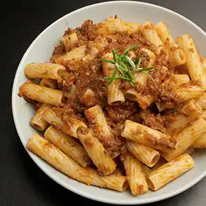 Teller mit Nudeln, Fleischsauce, Tomaten und Karotten.