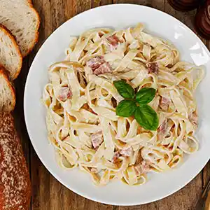 Teller mit Nudeln, Schinken und Sahnesauce.