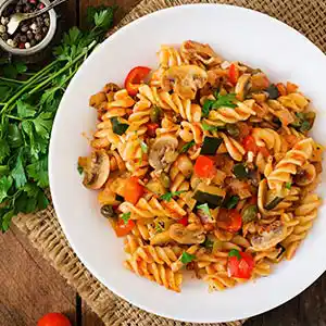 Teller mit Nudeln, Zucchini, Pilzen und Kapern.