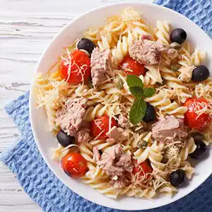 Teller mit Nudeln, Thunfisch, Tomaten, Käse und Oliven.