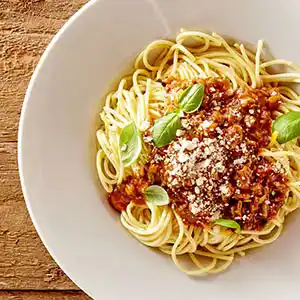 Teller mit Nudeln, Rinderhack, Tomaten und Käse.