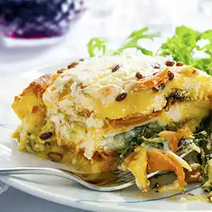 Teller mit Gemüse-Lasagne und Käse an Bechamelsauce.
