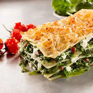 Teller mit Lasagne und Spinat, Käse an Bechamelsauce.