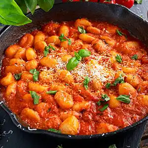 Teller mit Gnocci und Gemüse, Käse an Tomatensauce.