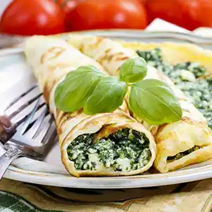 Teller mit Pfannkuchen und Spinat-Riccota-Käsefüllung.