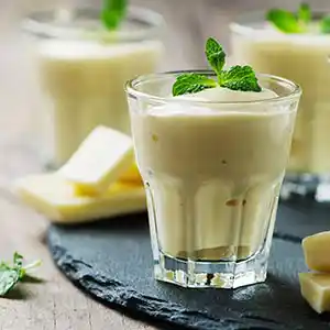 Teller mit weißem Schokoladen-Mousse, Sahne und Minz-Garnitur.