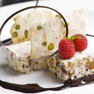 Weißer Torrone mit Früchten und Minzgarnitur.