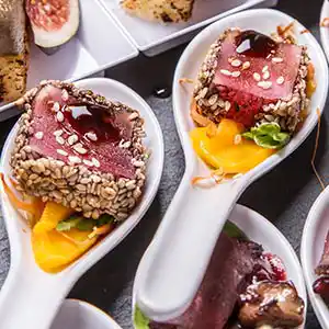 Löffel mit rosa gebratener Entenbrust im Kräutermantel auf Mangopüree.