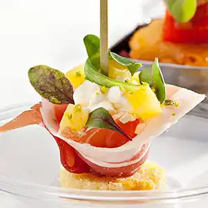 Parma Schinkenröllchen auf Bisquitetaler gefüllt mit Fruchtsalat.