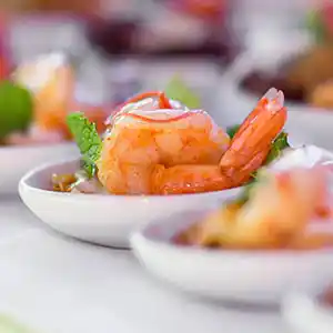 Löffel mit gebratenen Garnelen auf eingelegten Zitronen mit Minze.