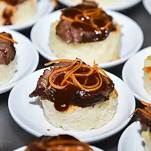 Schälchen mit Pulled Pork auf Weißbrottaler an BBQ-Sauce mit Karotten.