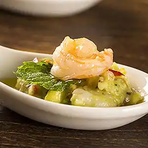 Löffel mit Shrimps auf Guacamole mit Minzgarnitur.