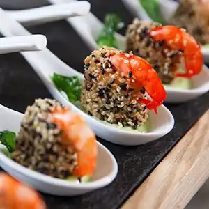 Löffel mit Garnelen im Sesam-Knuspermantel auf Gurke mit Pesto.