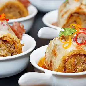 Löffel mit Krautwickerl und Lamm-Hackfleischfüllung an Schmorsauce.