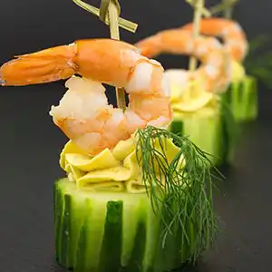 Gebratene Garnelen auf Gurkensockel und Ingwer mit Dill am Spieß.