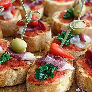 Tapas - Serano Schinken auf Tomatensugo und Weißbrot am Spieß.