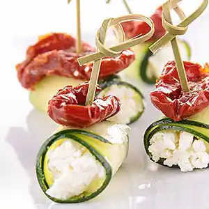 Gurken-Röllchen gefüllt mit Hüttenkäse an Trockentomaten am Spieß.