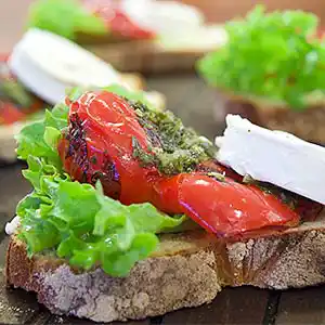 Ziegenkäse auf Toskana-Brot mit gegrillter Paprika an Rucola-Pesto.