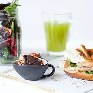 Holzbrett mit Breze, San Daniele Schinken, gemischter Salat, Zitronen-Ingwerlimonade und Cookie.