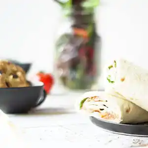 Holzbrett mit Wraps, Lachsfüllung und Sauce, gemischter Salat mit Kernen und Cookie.