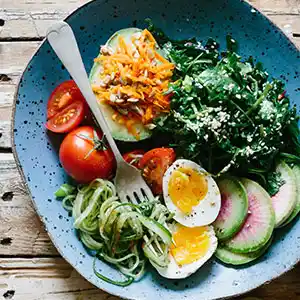 Salatteller mit Spinat, Avocado, Gurken, Tomaten, Ei und Feigen.