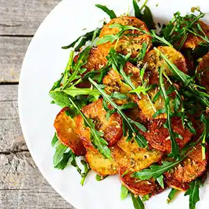 Bratkartoffelsalatteller mit Rucola, Tomaten, Schafskäse und Oliven.