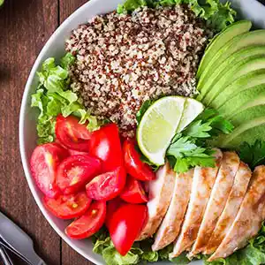 Salatteller mit Couscous, Tomaten, Avocado, Hünchenbrust und Limone.