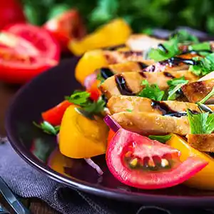 Salatteller mit gebratener Hühnerbrust, Paprika, Tomaten und Petersilie.