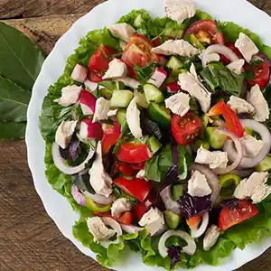 Blattsalatteller mit Tomaten, Oliven, Gurke, Ziebeln und Mozarella.