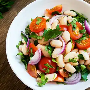 Weißer Bohnensalatteller mit Tomaten, Zwiebeln und Petersilie.