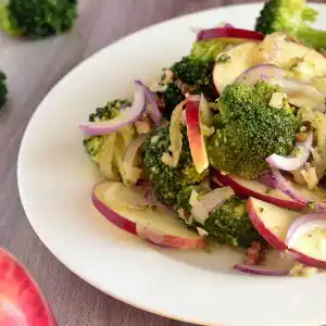 Salatteller mit Broccholi, Zwiebeln, Apfel und verschiedenen Nüssen.
