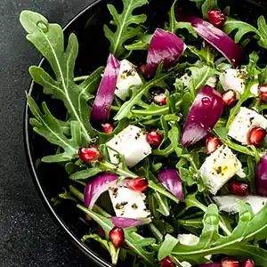 Rucolasalatteller mit Zwiebeln, Granatapfelkernen, Schafskäse.