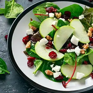 Salatteller mit Spinat, Cranberries, Radicchio, Apfel und Nüssen.