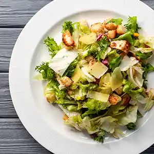 Teller mit Frisée, Salatherzen, Croutons, Parmesan und Birnen.