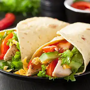 Wrap mit Hühnerbrust, Salat, Gurken, und Tomate.