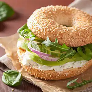 Bagel mit Frischkäse, Rucola, Zwiebeln und Avocado.