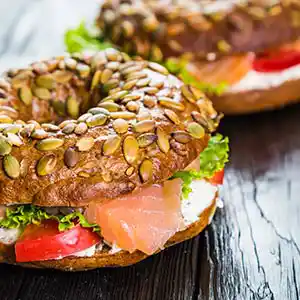 Bagel mit Frischkäse, geräucherter Lachs, Salat und Tomate.