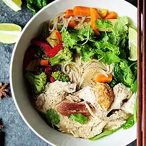 Teller mit chinesischer Nudelsuppe und Gemüse.