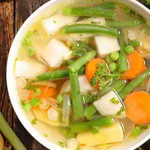 Teller mit klarer Gemüsesuppe, vegetarisch.