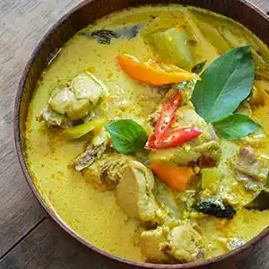 Teller mit Thaisuppe, Hühnchen und Curry.