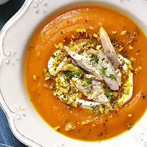 Teller mit Kürbissuppe und Hühnerbrust.