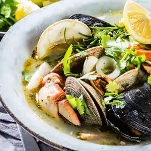 Teller mit Meeresfrüchtesuppe und Petersilie.