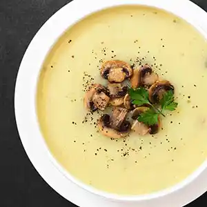 Teller mit Champinions-Suppe und Petersilie.